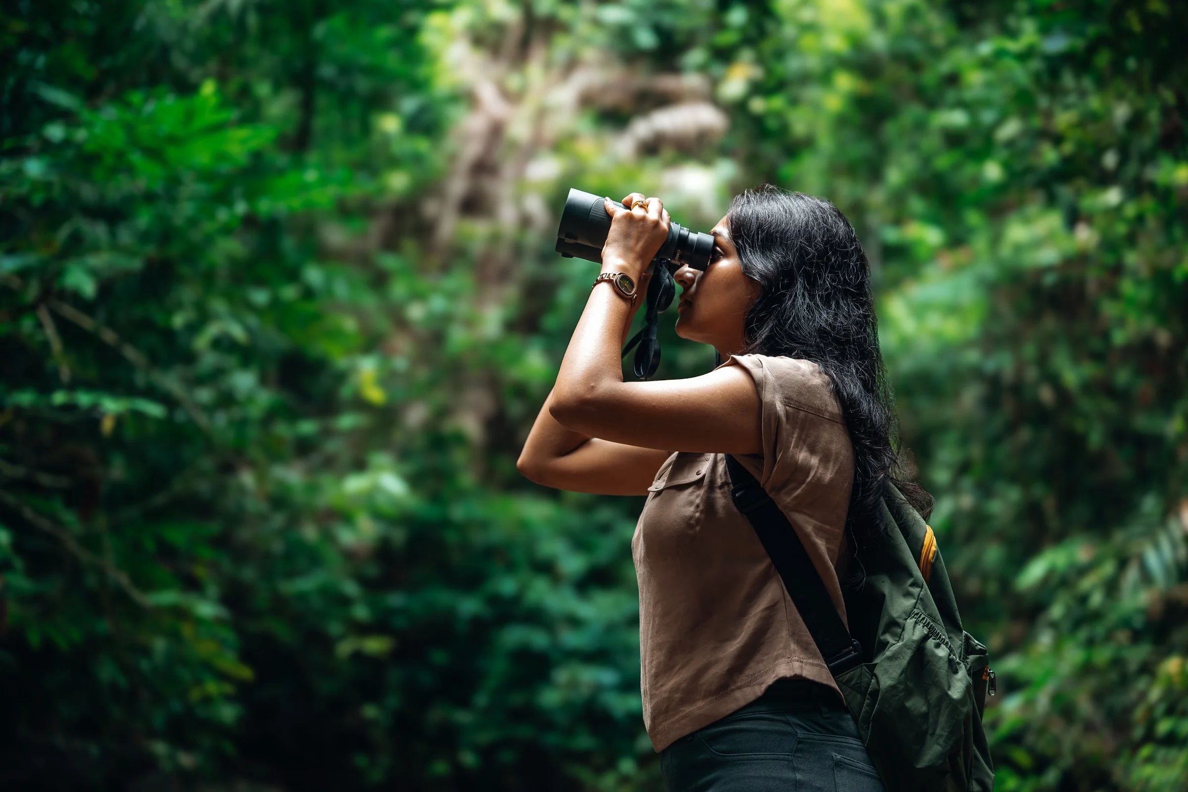 A person observing through binoculars in a forest
