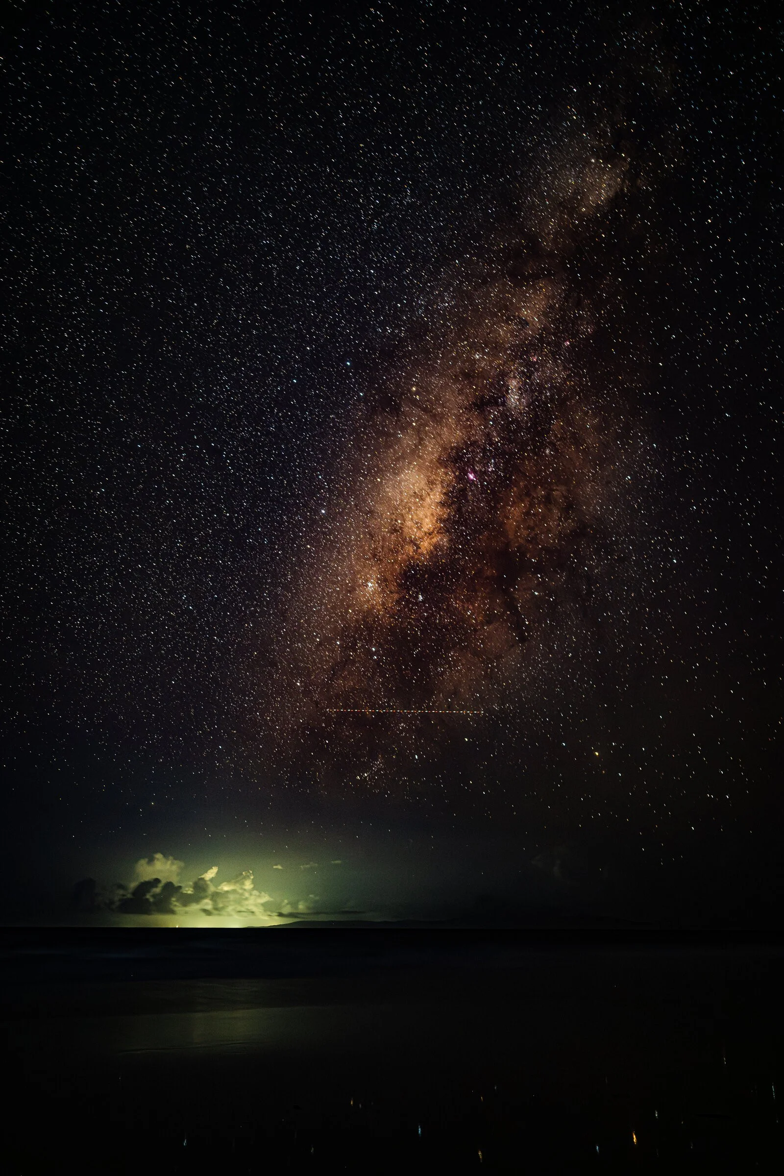 A star-filled night sky above a dark shoreline